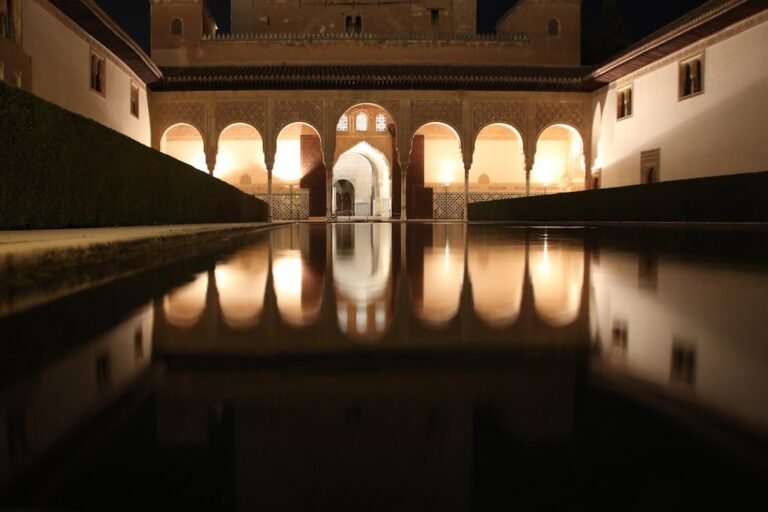 La cour des Myrtes de l’Alhambra de nuit, ses arcades reflétées dans le bassin