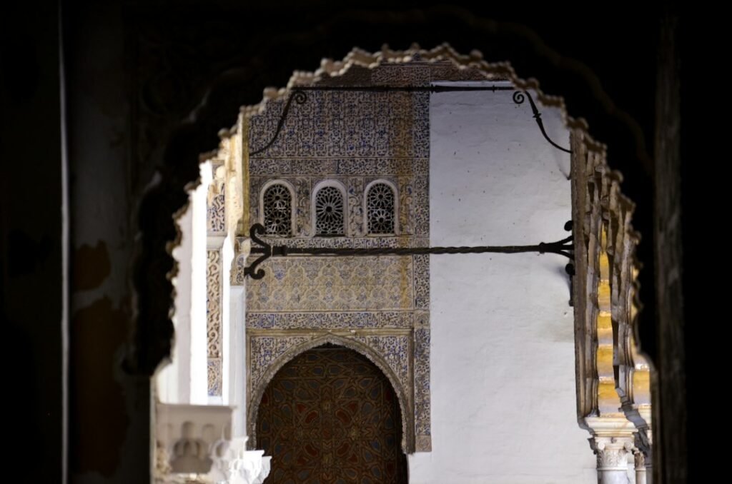 Photo : FotoFlo sur Unsplash Patio de l’Alcazar de Séville vu à travers un arc sculpté
