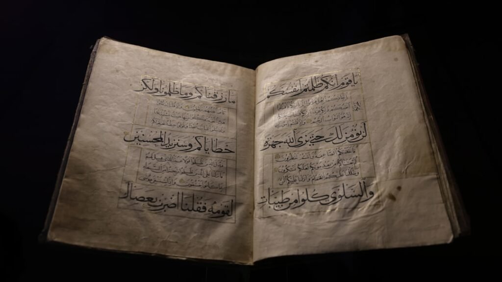 Coran manuscrit ancien ouvert, présenté sur fond noir