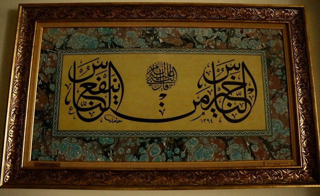 Calligraphie arabe à l’encre noire sur fond doré, dans un cadre ouvragé