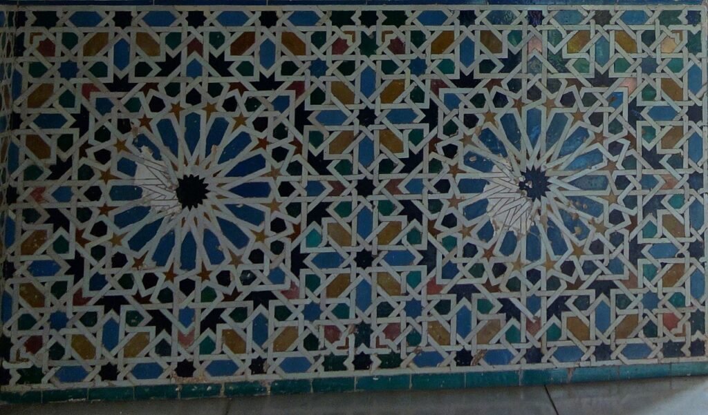 Photo : FlyingCrimsonPig, CC BY 2.0, Wikimedia Commons Décor de céramique à étoiles entrelacées de la tour de la Captive, à l’Alhambra